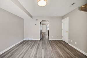 Empty room featuring arched walkways, wood finished floors, and a textured ceiling