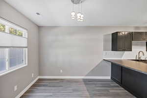 Kitchen with decorative light fixtures, backsplash, light wood-style floors, and a chandelier