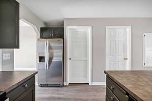 Kitchen featuring stainless steel fridge, light wood-style flooring, and dark cabinets