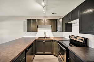 Kitchen featuring electric stove, backsplash, dishwasher, dark countertops, and light wood-style flooring