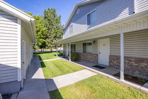 View of exterior entry with a lawn, covered porch, and brick siding