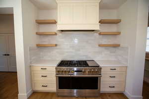 Kitchen with floating shelves, double oven range, light countertops, and light LVP floors