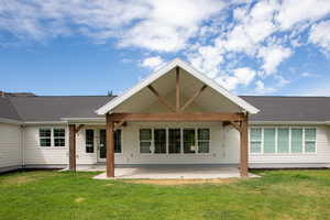 Back of house featuring a large covered patio area, a yard, and roof with shingles