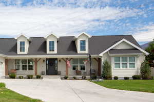 Craftsman home with covered porch, roof with shingles, a large front lawn, and board and batten siding