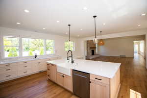 Kitchen featuring light LVP flooring, stainless steel dishwasher, a fireplace, recessed lighting, and light countertops