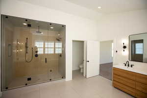 Bathroom featuring a shower stall, double vanities, tile patterned flooring, lofted ceiling, and recessed lighting