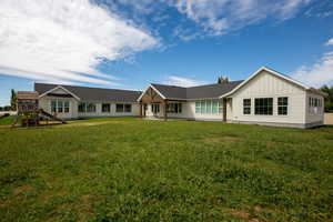 Rear view of property with a playset, board and batten siding, covered patio and large