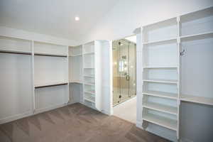 Spacious master closet featuring vaulted ceiling and carpet floors