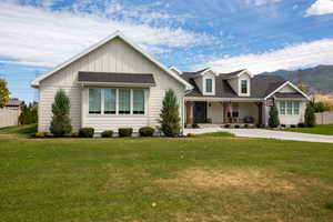 View of front of property with board and batten siding, roof with shingles, and driveway
