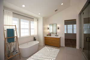 Master bath with two vanities, a soaking tub, vaulted ceiling, tile patterned flooring, and a tiled oversize shower - Virtual Staging.