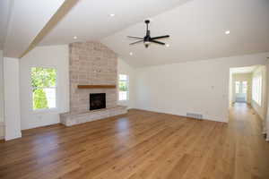 Family room featuring plenty of natural light, a fireplace, LVP floors, high vaulted ceiling, and recessed lighting