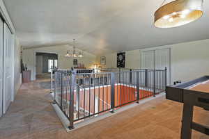 Hall featuring a textured ceiling, carpet, an upstairs landing, and vaulted ceiling