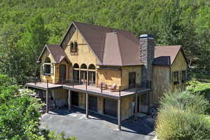 Back of property featuring roof with shingles, driveway, a chimney, and a garage