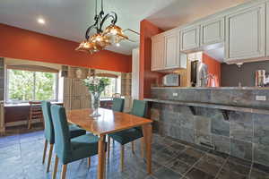 Dining space featuring stone tile flooring and a chandelier