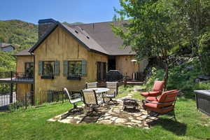Rear view of property featuring a patio area, an outdoor fire pit, a shingled roof, and a chimney