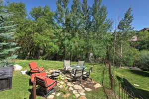View of green lawn featuring an outdoor fire pit and a patio area