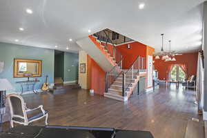 Living room featuring stairway, dark wood finished floors, recessed lighting, and a chandelier