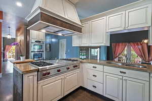 Kitchen with premium range hood, dark wood finished floors, a textured ceiling, stainless steel appliances, and a peninsula