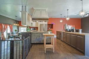 Kitchen with a chandelier, hanging light fixtures, a textured ceiling, dark wood finished floors, and premium range hood
