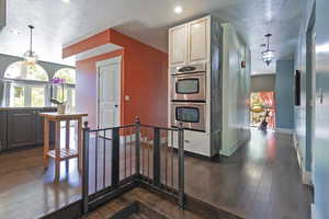 Corridor featuring a textured ceiling, a chandelier, dark wood-style floors, an upstairs landing, and recessed lighting