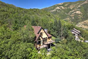Aerial view of property and surrounding area with mountains and a forest