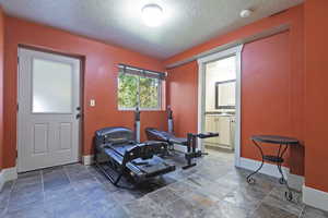 Workout area with a textured ceiling and stone finish floors