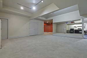 Unfurnished living room featuring track lighting and light carpet