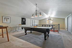 Rec room featuring billiards table, light colored carpet, a textured ceiling, and lofted ceiling