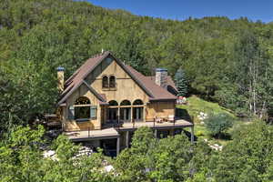 Rear view of property featuring a chimney, a view of trees, and a wooden deck