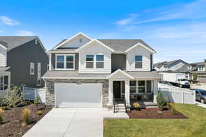 Craftsman inspired home with a garage, concrete driveway, covered porch, stone siding, and roof with shingles