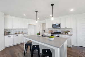 Kitchen with quartz countertops, large island, tile backsplash, and gas range