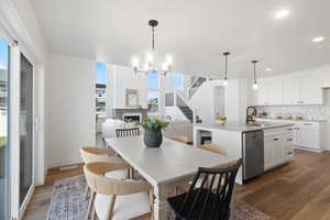 Dining area with stairway, dark wood-style flooring, a chandelier, a fireplace, and recessed lighting