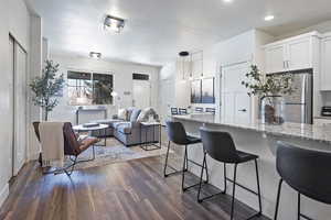 Kitchen featuring light stone counters, a kitchen bar, white cabinets, freestanding refrigerator, and a textured ceiling