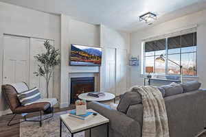 Living area featuring wood finished floors, a glass covered fireplace, and a textured ceiling