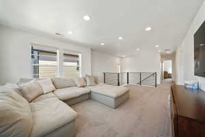 Living area with light carpet and recessed lighting