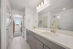 Bathroom with double vanity, a stall shower, and light tile patterned floors