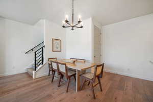 Dining space with light wood-style flooring, a chandelier, and stairway