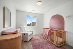 Carpeted bedroom featuring a nursery area and baseboards
