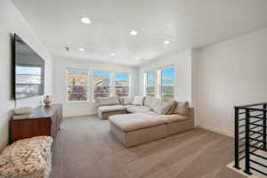 Living area with light colored carpet and recessed lighting