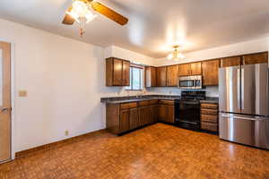 Large open kitchen with dark countertops, stainless steel refrigerator & microwave.