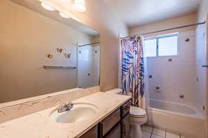 Full bath featuring shower / bath combo, large vanity, carpet  & light tile floors