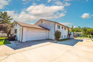 View of the side of the home with RV parking,  driveway, an attached garage, and the roof with asphalt shingles