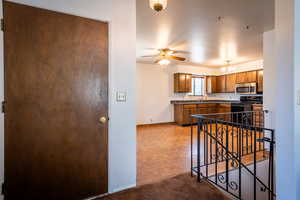Kitchen featuring dark countertops, brown cabinets, stainless steel microwave, and black range with electric cooktop