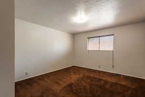Bedroom #1 Large bedroom featuring dark colored carpet and a textured ceiling
