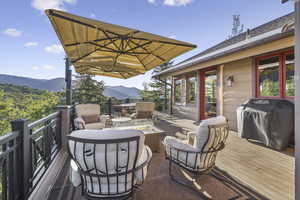 Wooden deck featuring a mountain view, an outdoor living space with a fire pit, and area for grilling