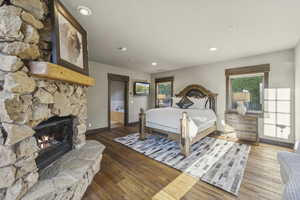 Bedroom featuring multiple windows, hardwood / wood-style flooring, recessed lighting, a fireplace, and ensuite bath