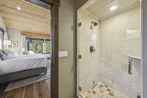 Ensuite bathroom featuring a stall shower, recessed lighting, and wood finished floors