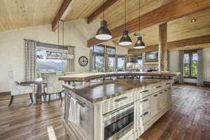 Kitchen featuring butcher block counters, pendant lighting, dark wood finished floors, high vaulted ceiling, and a kitchen island