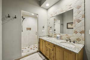 Full bathroom with a shower stall, double vanity, and backsplash