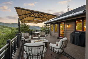 Wooden terrace with an outdoor living space with a fire pit, a grill, and a mountain view